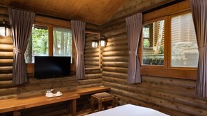 A log cabin room with a bed, a TV, a table with cups and a tray, and curtains on the windows. - Mingchih Resort (Datong)