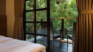 A bedroom with a large window overlooking a wooden deck and lush greenery. - Mingchih Resort (Datong)