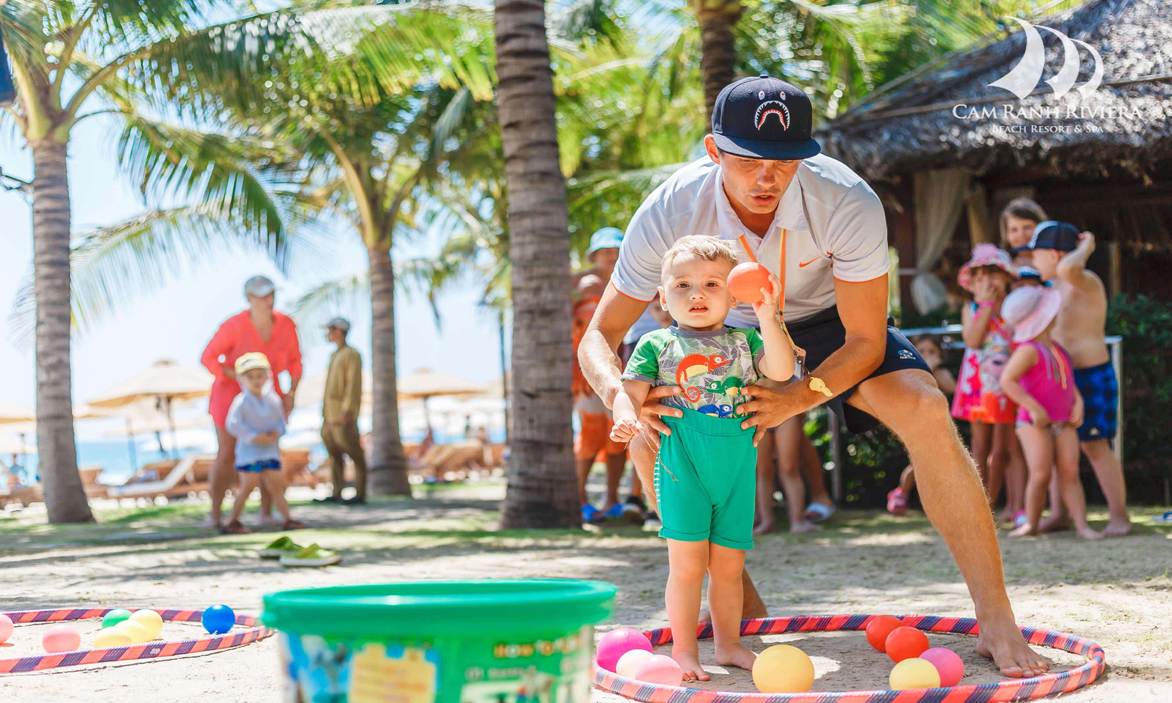 A beach scene with palm trees, people, and a beach ball game.
