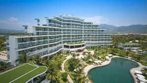 A multi-story hotel with a pool, surrounded by greenery and palm trees. - Cam Ranh Riviera Beach Resort & Spa (Cam Lam)