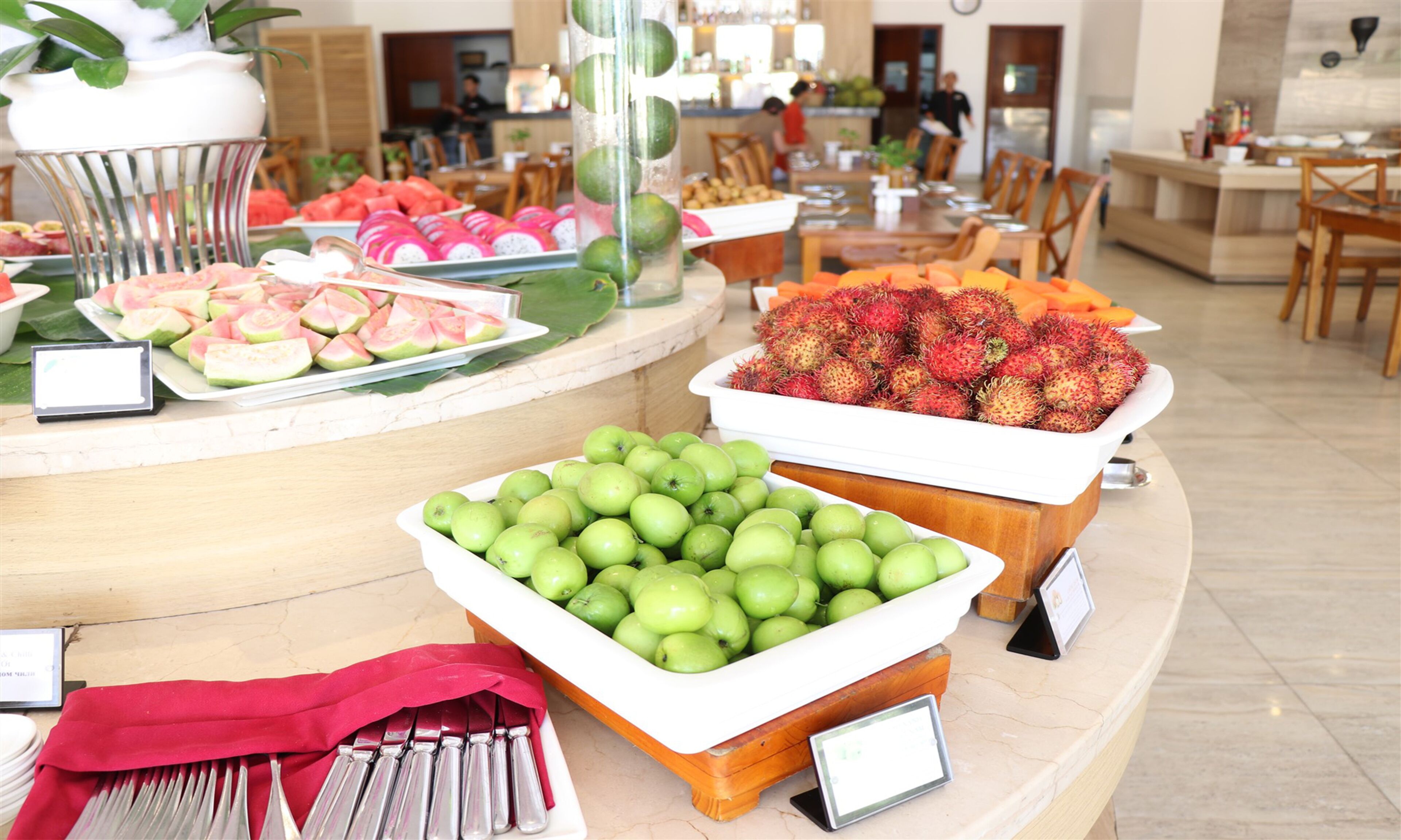 A buffet with various fruits and vegetables, including watermelon, dragon fruit, and green apples.