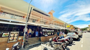 A restaurant with outdoor seating and a sign indicating it serves American breakfast. - Dome Resort (Karon)