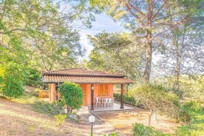 A small building with a tiled roof, surrounded by trees and vegetation. - Villaggio Colombo (Andora)