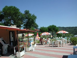 An outdoor seating area with umbrellas, chairs, and a pool.