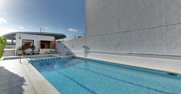 Una piscina al aire libre, sombrillas, sillones reclinables de piscina