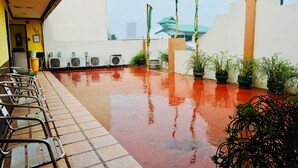 A wet terrace with chairs, potted plants, and air conditioning units. - Tinhat Boutique Hotel and Restaurant (Davao)