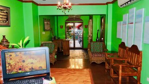 A room with green walls, a wooden desk with a laptop, a chandelier, and traditional furniture. - Tinhat Boutique Hotel and Restaurant (Davao)