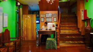 A reception desk with a man seated, a staircase, and a chandelier. - Tinhat Boutique Hotel and Restaurant (Davao)