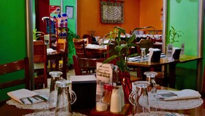 A restaurant with wooden tables set for dining, green walls, and a chandelier. - Tinhat Boutique Hotel and Restaurant (Davao)