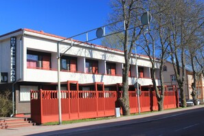 A hotel with a red fence, multiple windows, and a clear blue sky. - Hotel Esplanad (Mariehamn)