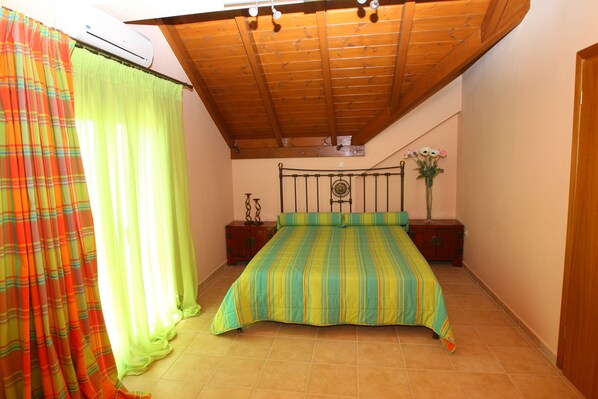 Un dormitorio con cama, cortinas, mesita de noche, cómoda y ventilador de techo.