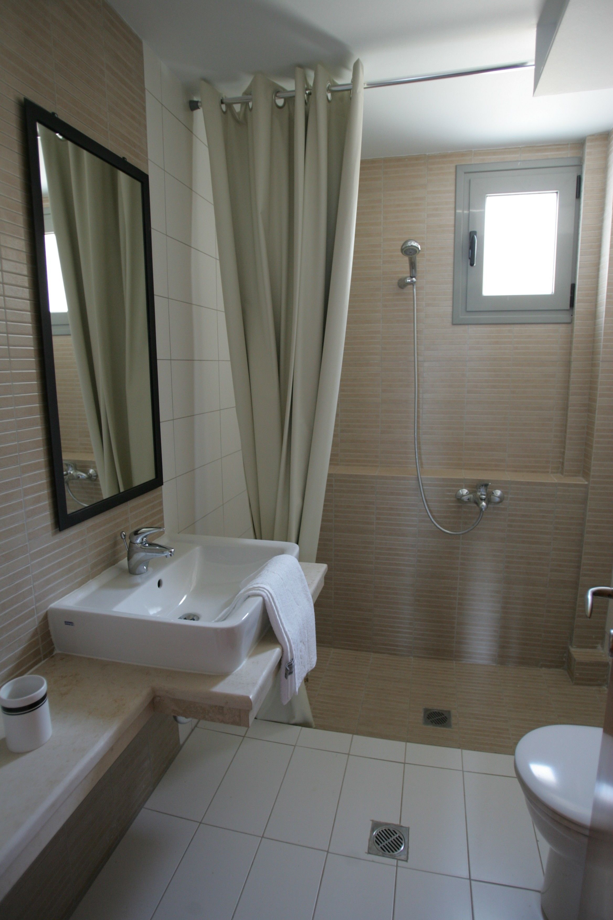 A bathroom with a sink, mirror, shower, and toilet.