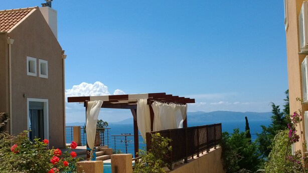 Une terrasse agrémentée d’une pergola, une piscine et une vue sur la mer et les montagnes.