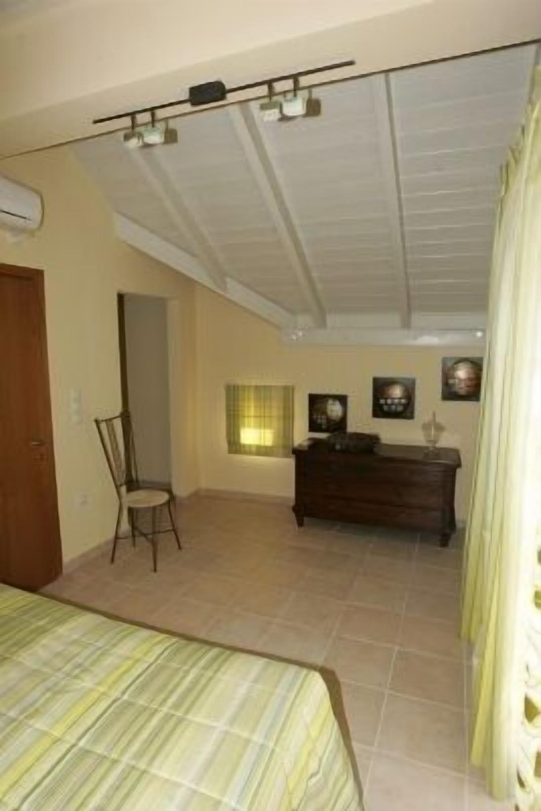 Un dormitorio con cama, cómoda, una silla y ventana con cortinas.