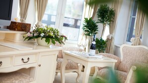 A well-lit room with a white vanity, a floral arrangement, a bottle of wine, and a sofa. - Hotel Szrenicowy Dwór (Szklarska Poreba)
