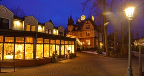 A historic building with large windows and a balcony, surrounded by trees and a cobblestone street. - Hotel Szrenicowy Dwór (Szklarska Poreba)
