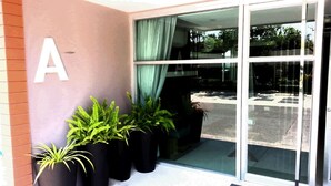 A building entrance with a large 'A' sign, glass doors, and potted plants. - Baan Khun Koey A414 by Huahin Holiday Condo (Hua Hin)