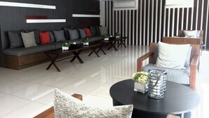 A modern living room with a sofa, coffee table, and armchairs. There is a large window and an air conditioning unit on the wall. - Baan Khun Koey A414 by Huahin Holiday Condo (Hua Hin)