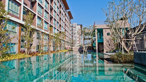 A modern hotel with a long swimming pool, multiple floors, and a mix of architectural styles. - Baan Khun Koey A414 by Huahin Holiday Condo (Hua Hin)