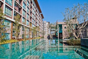 Un hotel moderno con una lunga piscina, diversi piani e un insieme di stili architettonici.