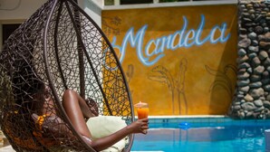 En person slapper af i en hængekøje ved en pool, 'Mandelia' står i baggrunden.