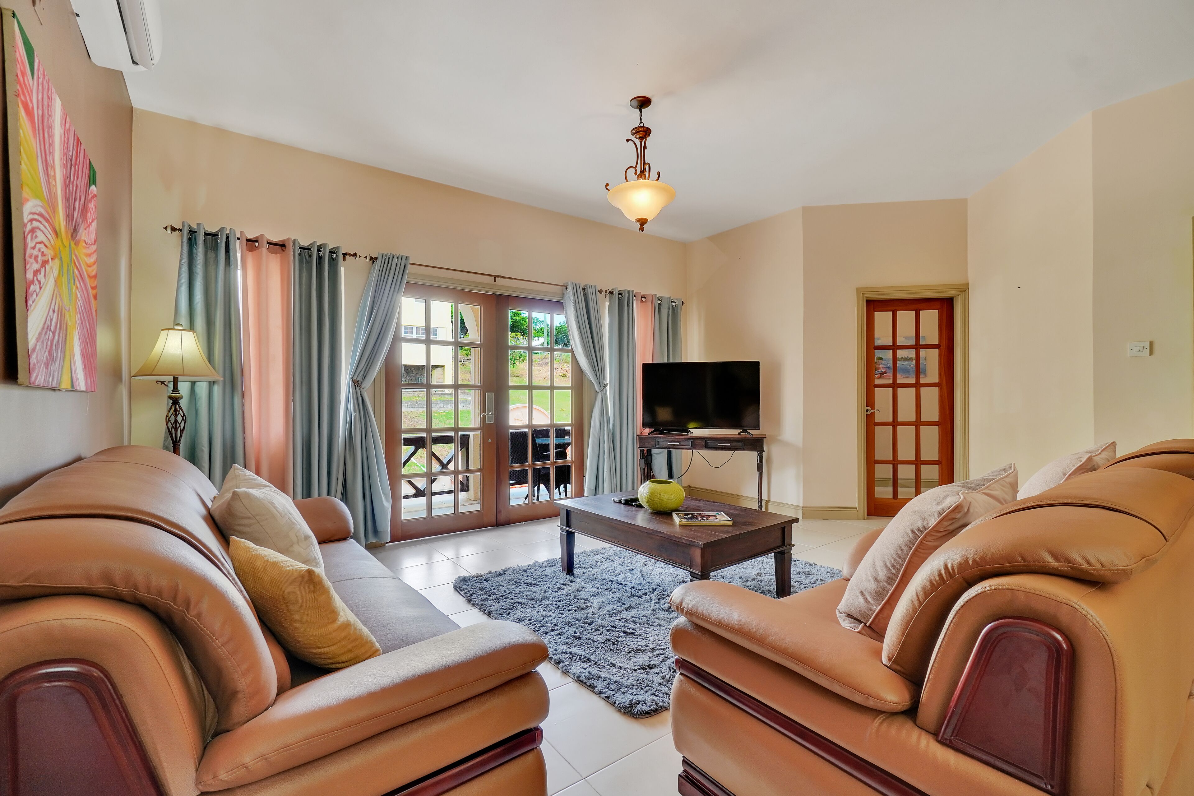 A living room with leather sofas, a coffee table, a TV, and a door.