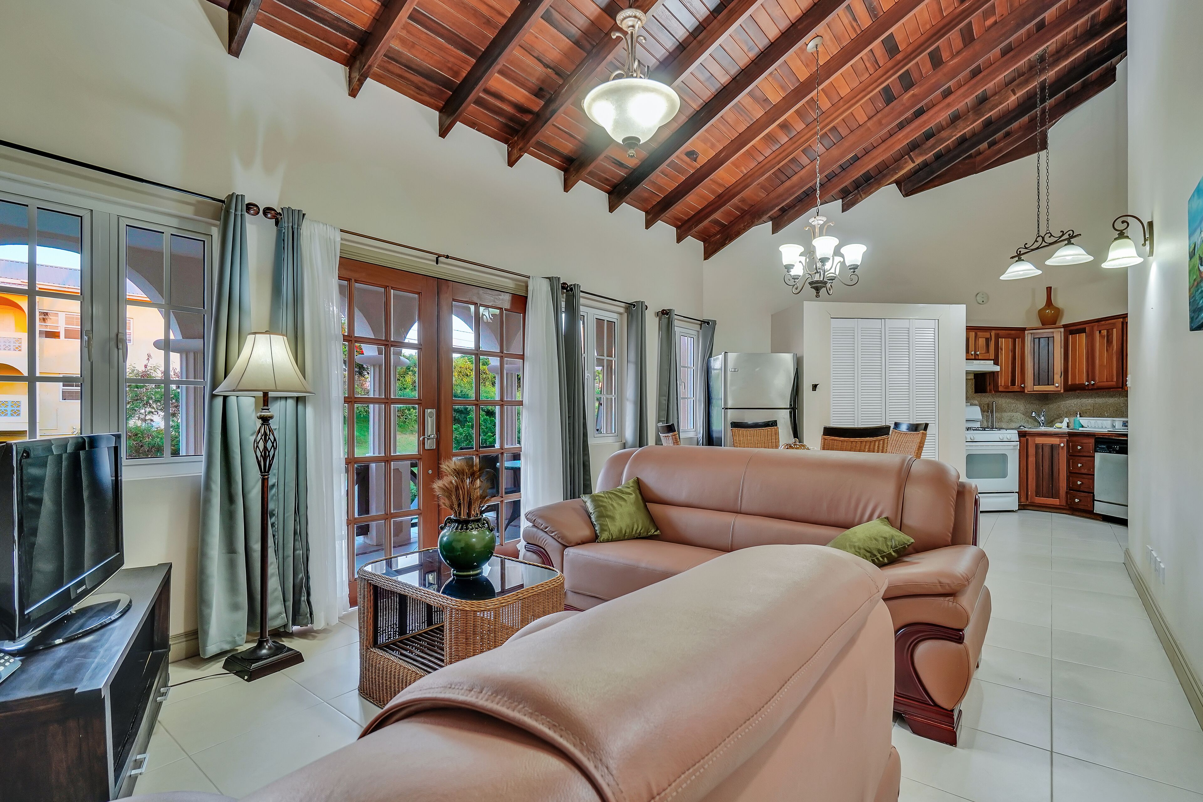 A spacious living room with a large sofa, a television, and a dining area in the background.