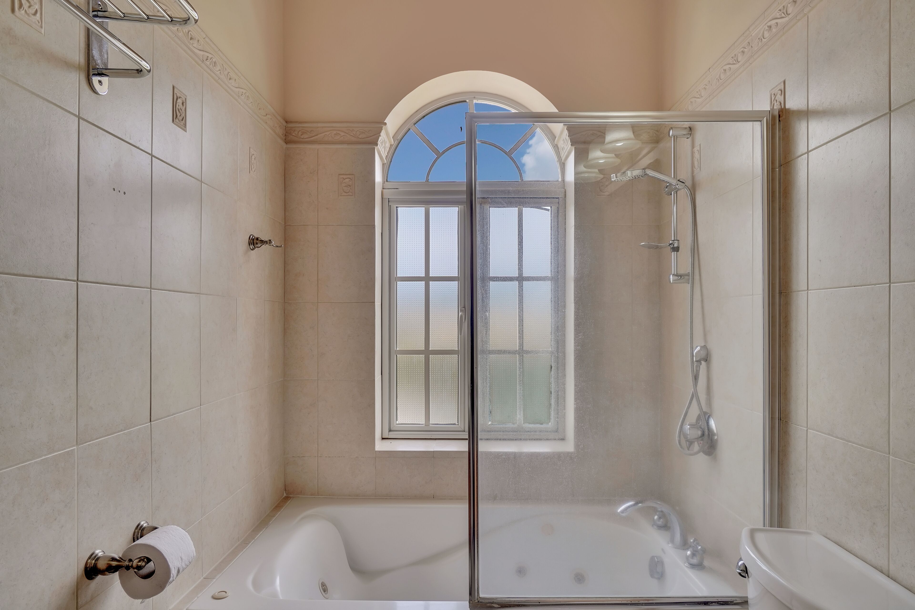 Un baño con ducha envuelta en vidrio, bañera y ventana con vistas.