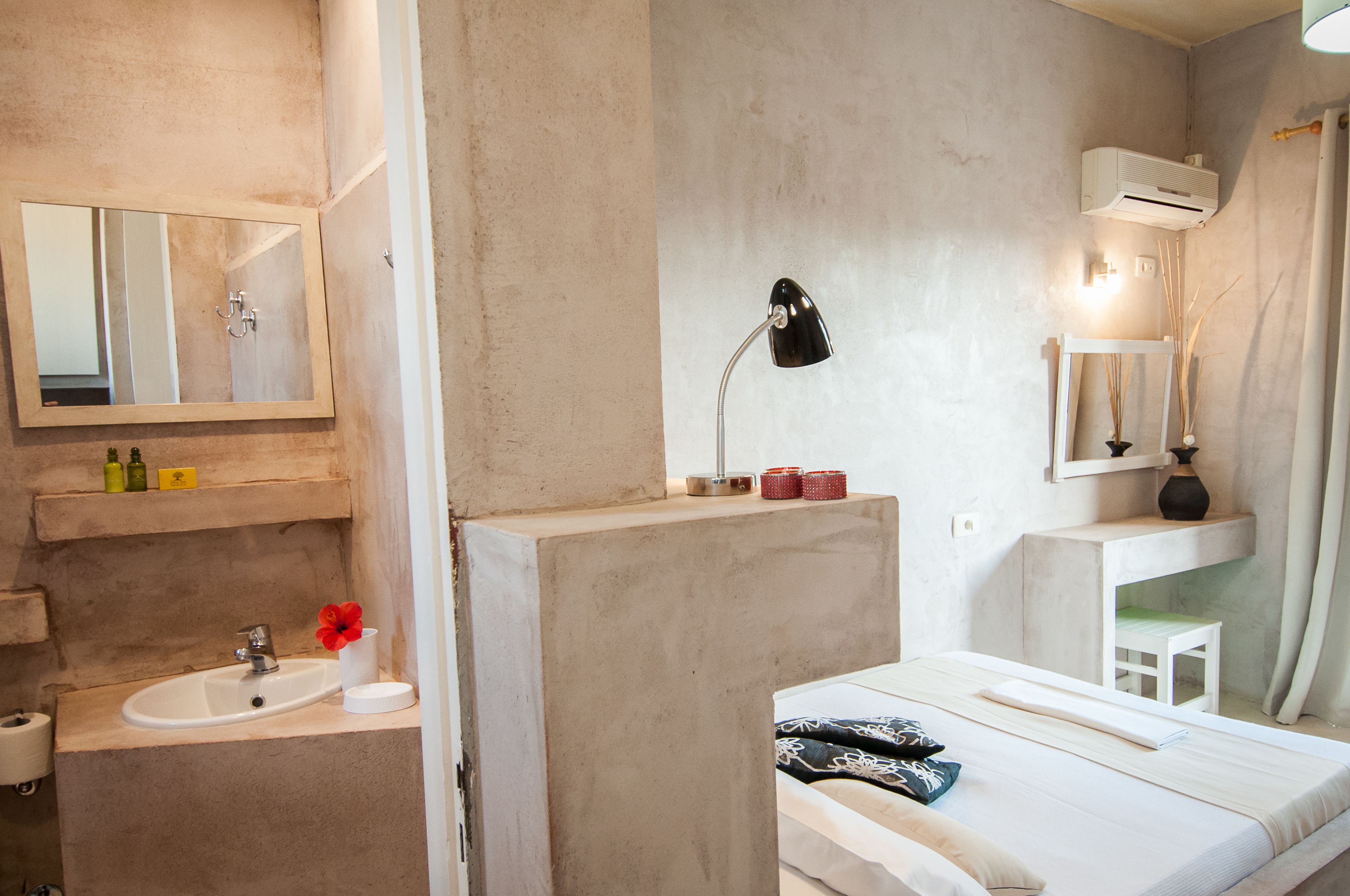 Een compacte hotelkamer met een eenpersoonsbed, een klein nachtkastje, een ingebouwd wastafeltje en een spiegel.