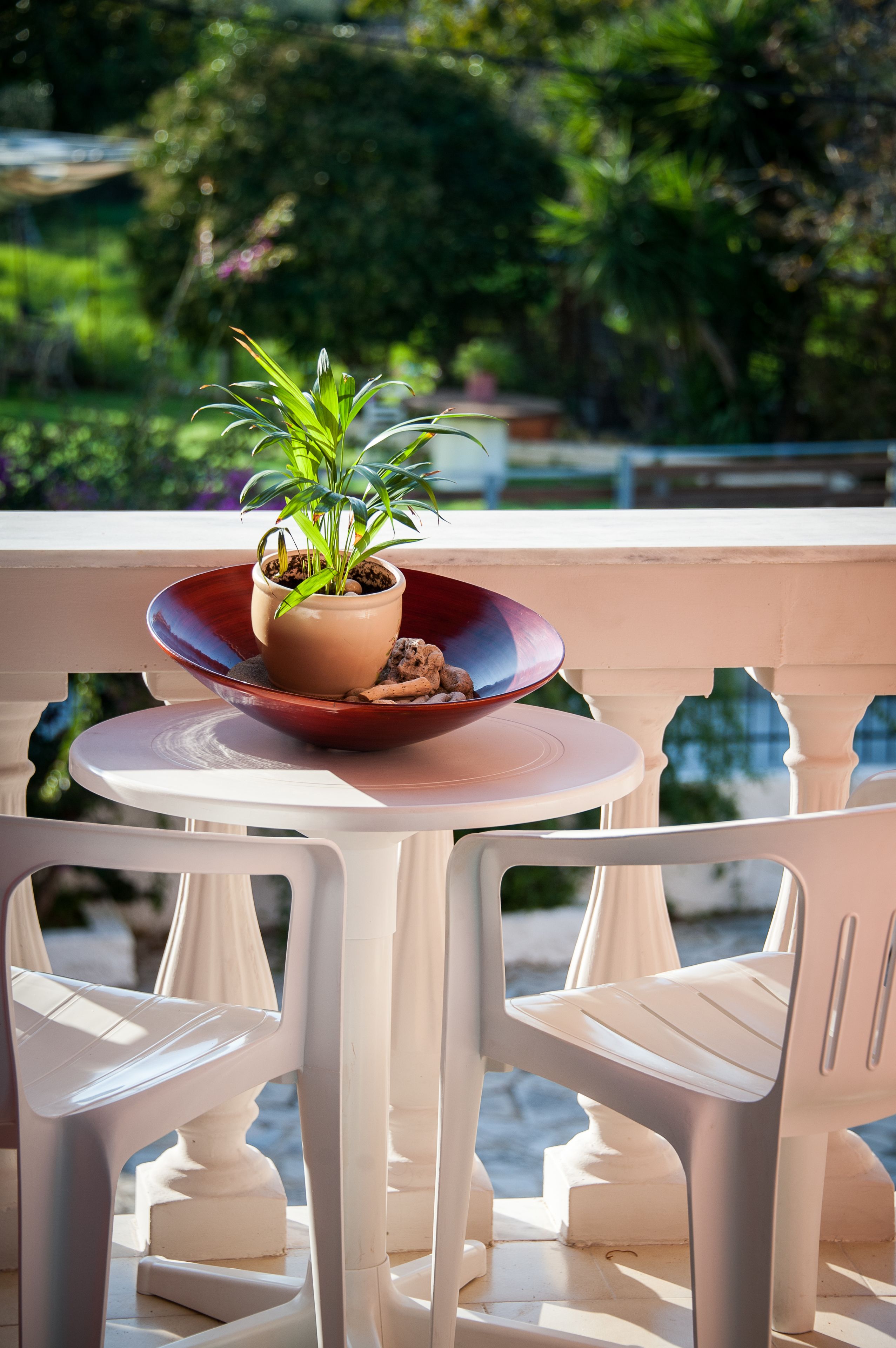 Un balcón con una mesa, sillas, una planta en maceta y un cuenco decorativo.