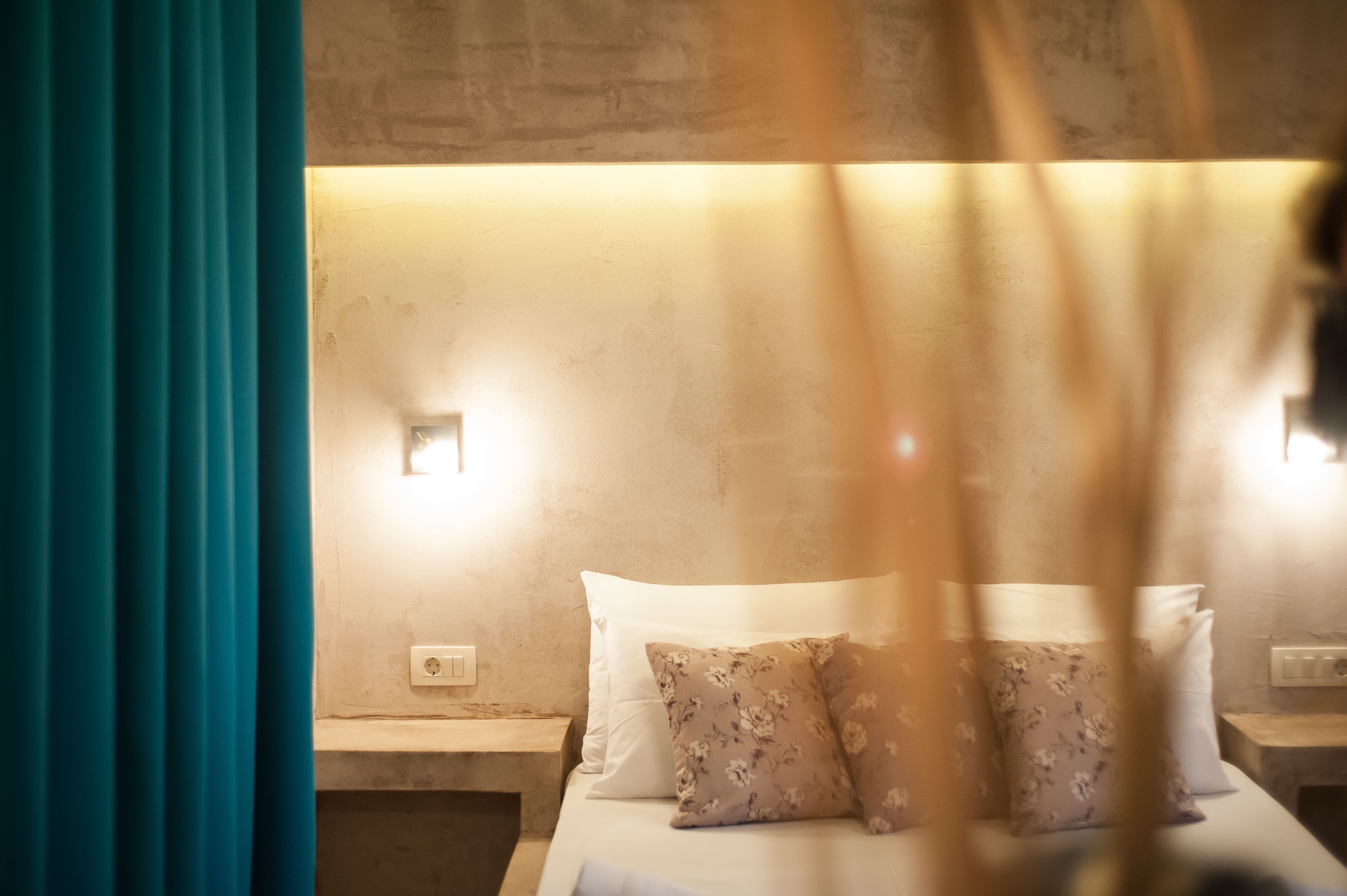 Une chambre d’hôtel avec un lit, deux tables de chevet et des lampes fixées au mur.