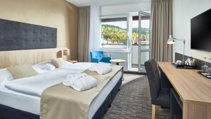 Habitación de hotel con una cama grande, un escritorio, una silla, un televisor y vistas al exterior.