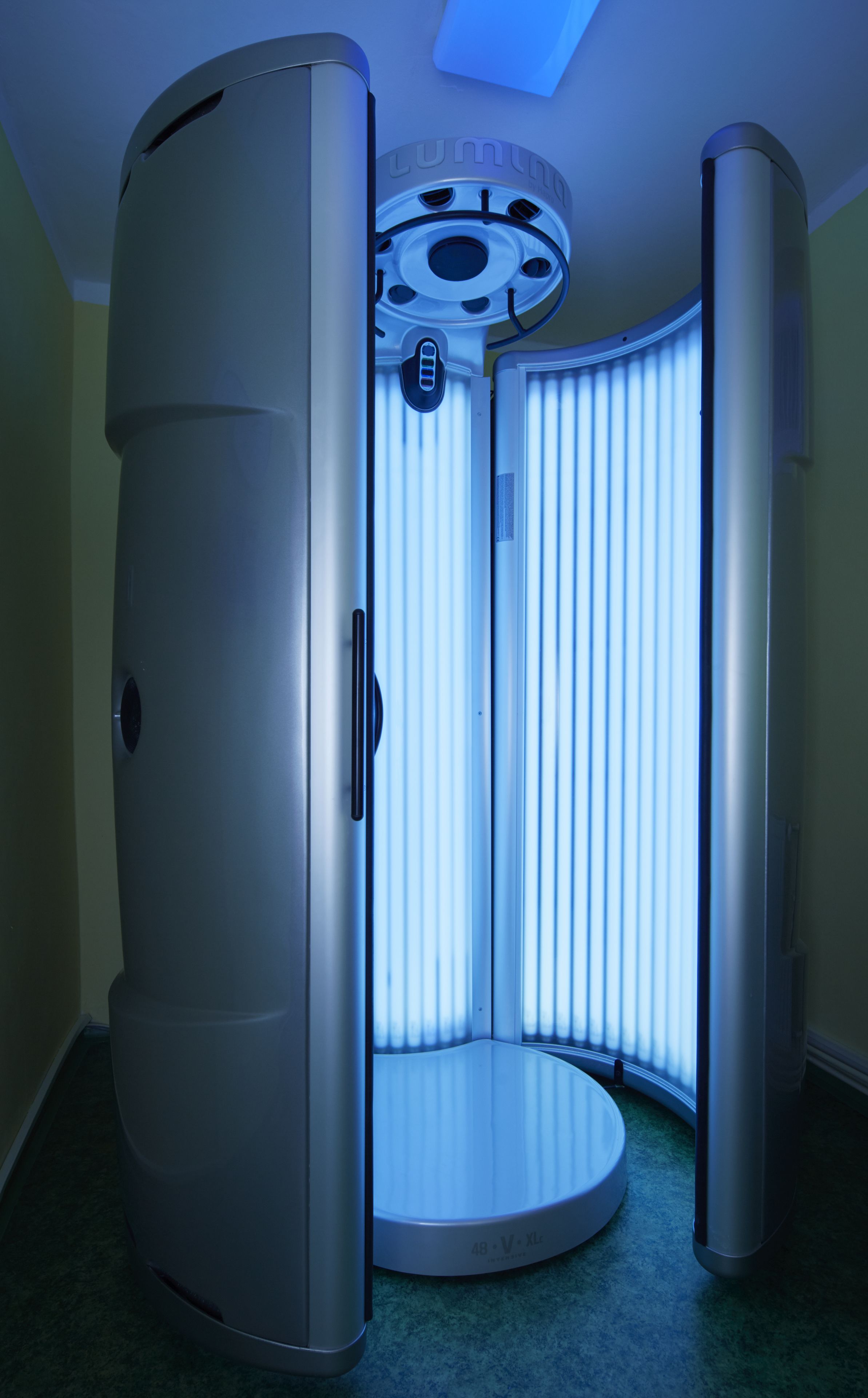A tanning booth with a circular design, a control panel, and a ventilation system.
