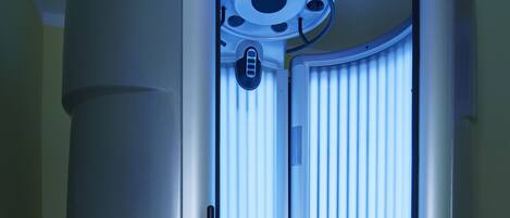 A tanning booth with a circular design, a control panel, and a ventilation system.