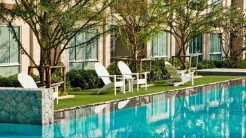 Una piscina al aire libre, sillones reclinables de piscina