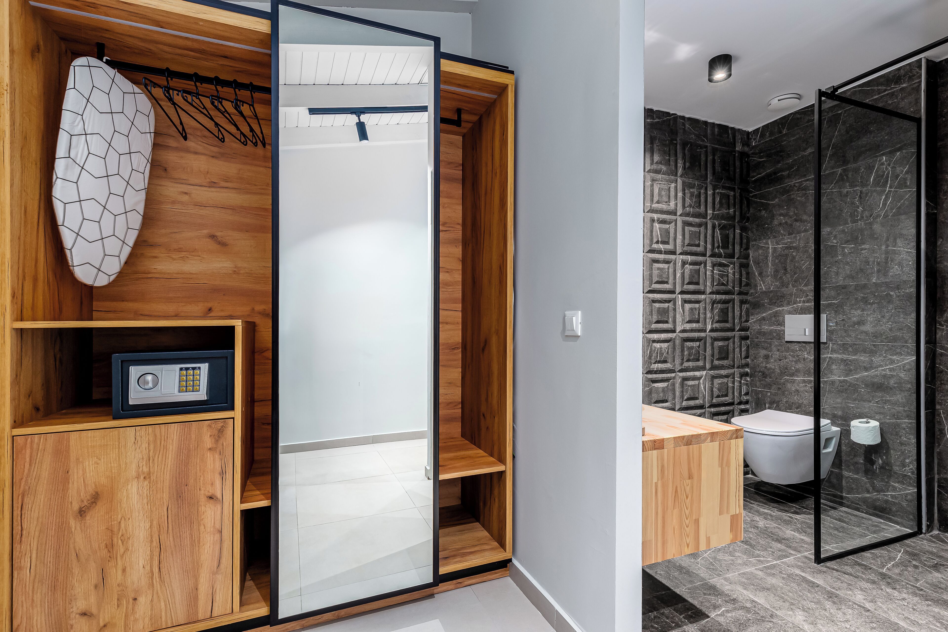 Ein modernes Badezimmer mit einem Holzbadezimmermöbel, einer Duschkabine aus Glas und einer Marmor-Spritzschutzwand.