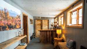 Une pièce chaleureuse avec un banc en bois, une petite table avec une lampe et un banc doté d’un coussin.