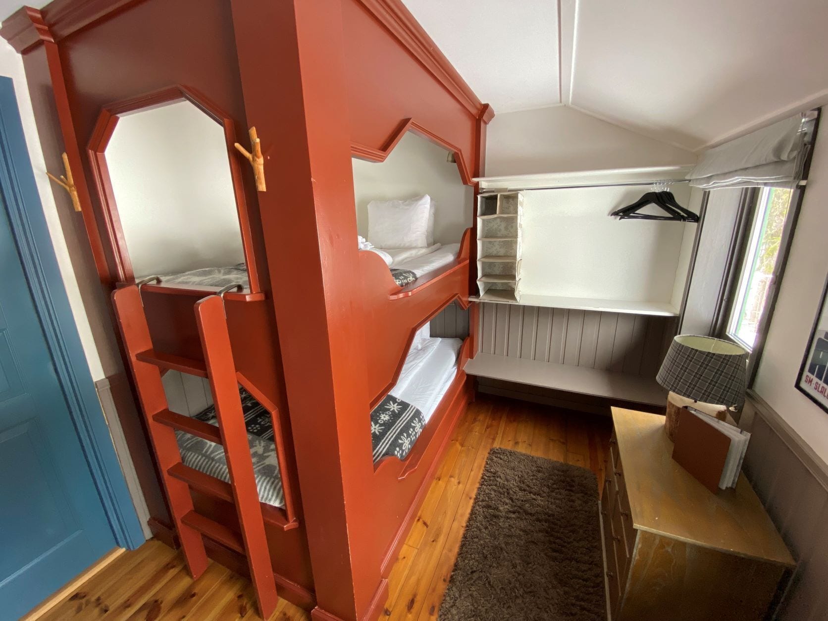 Habitación pequeña con literas, un escritorio, una silla y ventana con vistas.