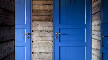 Dos puertas azules con el número 12, paredes de madera y un picaporte de metal.