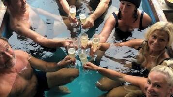 A group of people toasting with champagne in a small outdoor pool.
