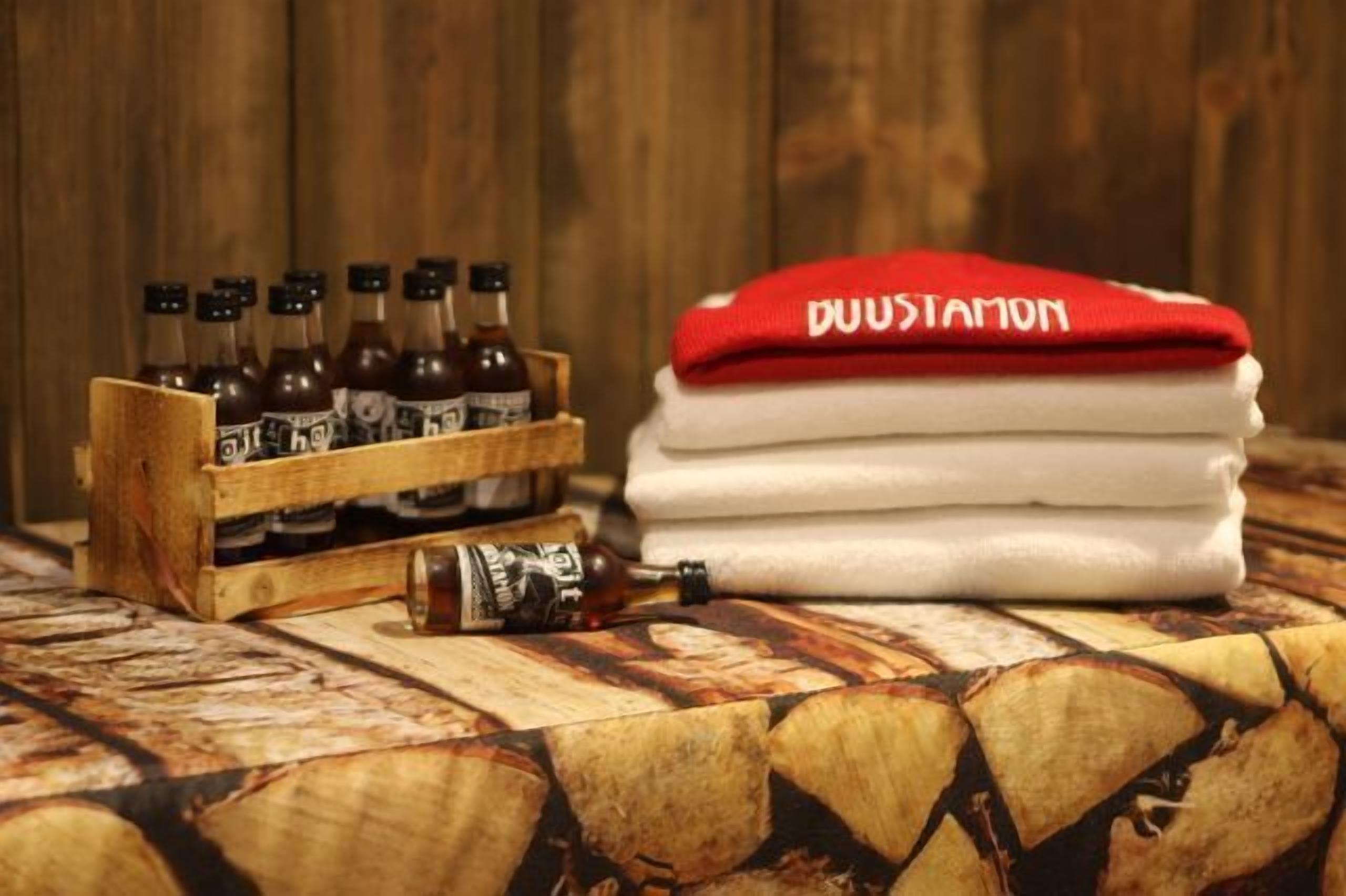 A wooden crate with bottles, a folded towel, and a bottle on a patterned surface.