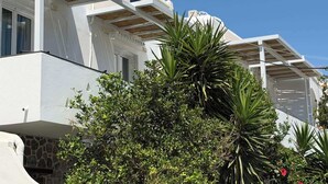 A white building with a wooden pergola and a stone wall. - Foinikas Studios (Kithnos)