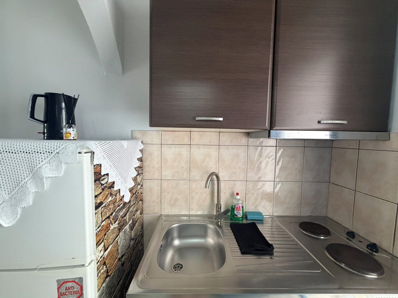 Uma cozinha com pia de aço inoxidável, cafeteira e fogão.