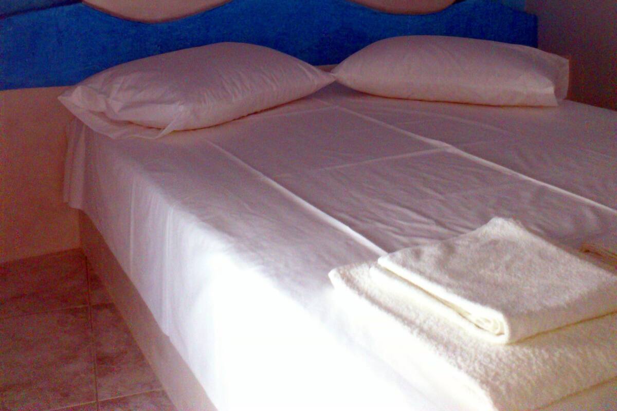 A bed with a headboard featuring a sailboat design, white bedding, and a folded towel.
