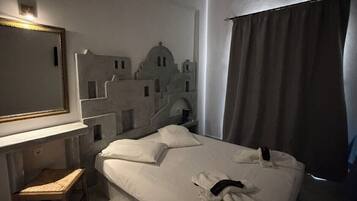 A hotel room with a bed, a desk, a chair, a mirror, and a wall decoration.
