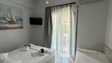 Una habitación con dos camas, un cuadro, un televisor y una ventana con cortinas.