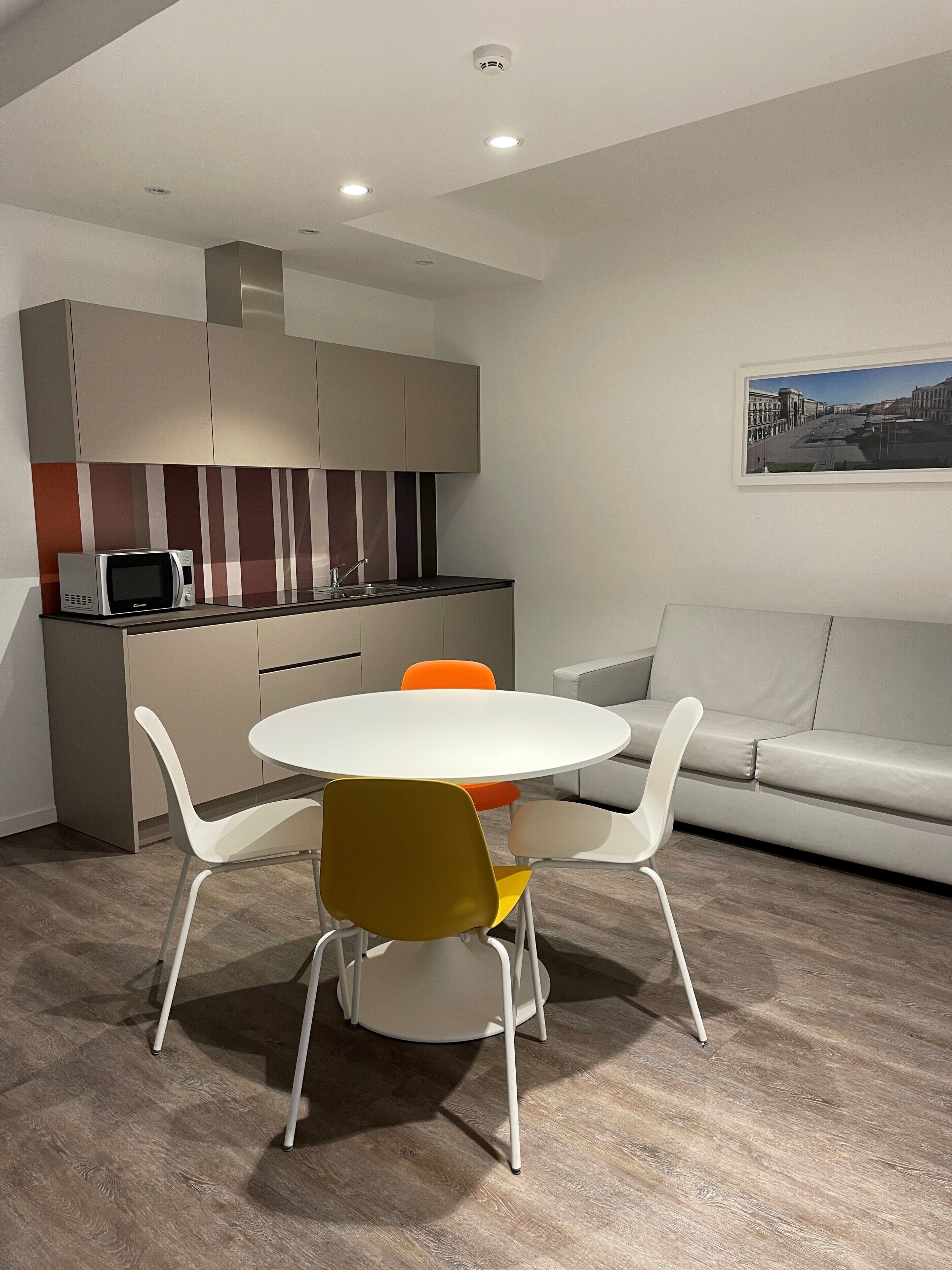Eine moderne Küche mit Mikrowelle, Spüle und einem Essbereich mit rundem Tisch und bunten Stühlen.