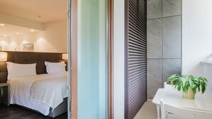 A hotel room with a bed, a bedside table, a chair, a small table with a plant, and a sliding door leading to another room. - Hotel Studio Inn Centrale & Milano Urban Padel (Milan)
