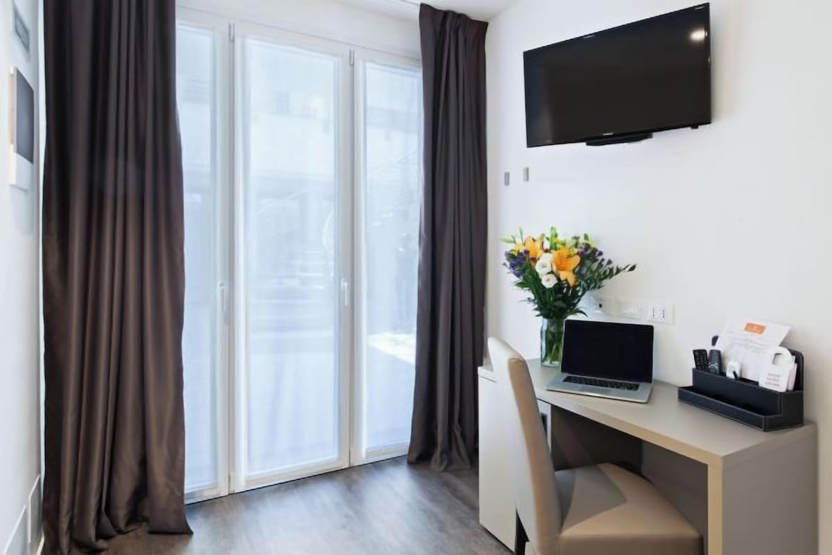 Une chambre d’hôtel équipée d’un bureau, d’un ordinateur portable et d’un téléviseur à écran plat.