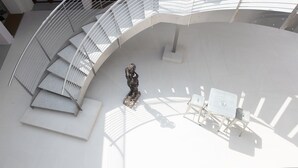 A modern interior with a curved staircase, a central sculpture, and a seating area with tables and chairs. - Hotel Studio Inn Centrale & Milano Urban Padel (Milan)